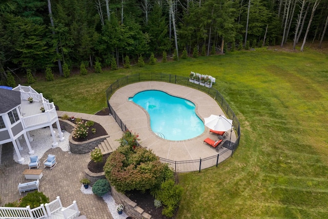 view of pool featuring a fenced in pool, a patio area, fence, a yard, and a view of trees