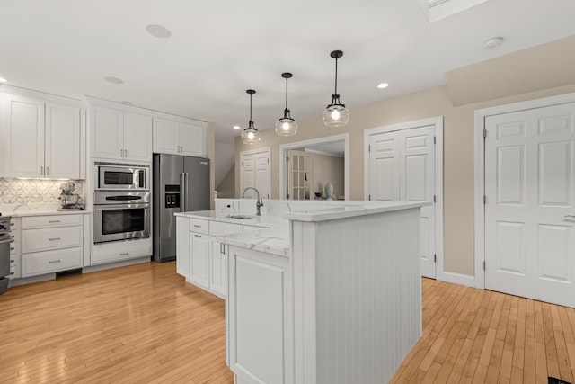 kitchen with white cabinetry, stainless steel appliances, light wood-style flooring, and a sink
