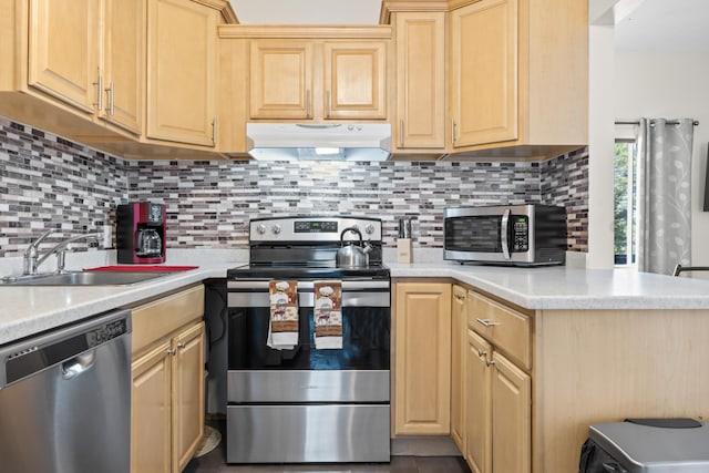 kitchen with a sink, appliances with stainless steel finishes, light countertops, under cabinet range hood, and light brown cabinetry