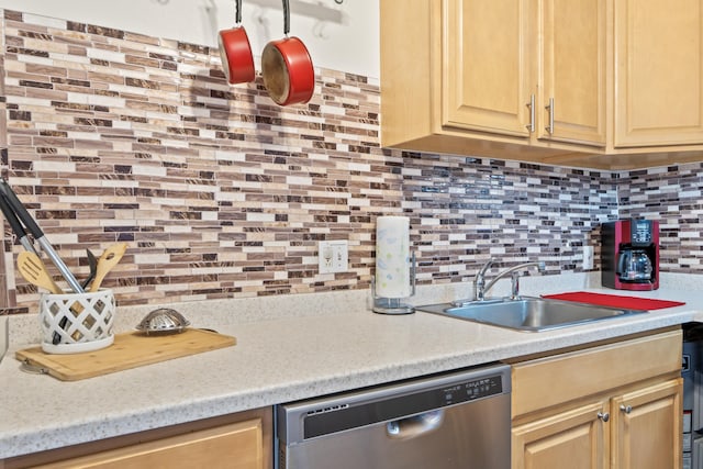 kitchen with backsplash, light countertops, stainless steel dishwasher, and a sink