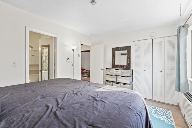 bedroom with a closet, wood finished floors, and ensuite bathroom