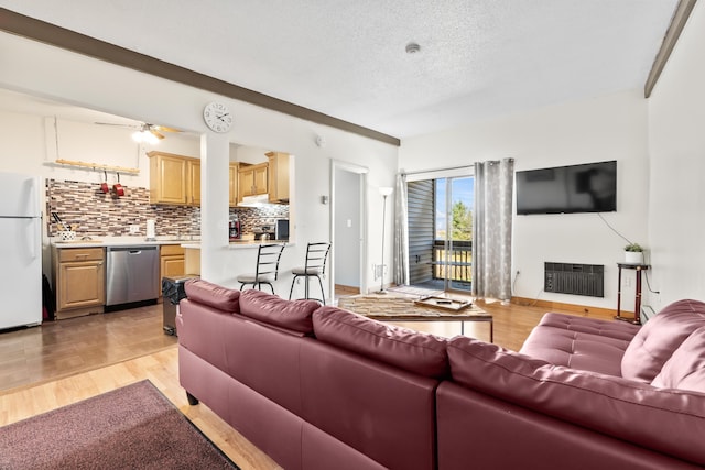 living room with a textured ceiling, ceiling fan, and light wood-style flooring