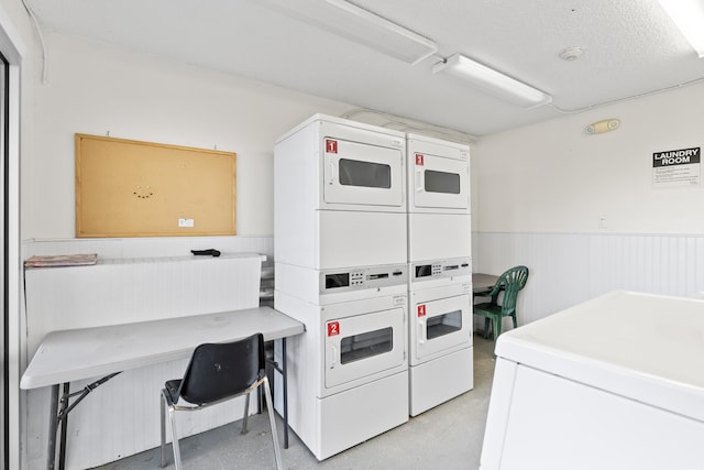 community laundry room with stacked washing maching and dryer and wainscoting