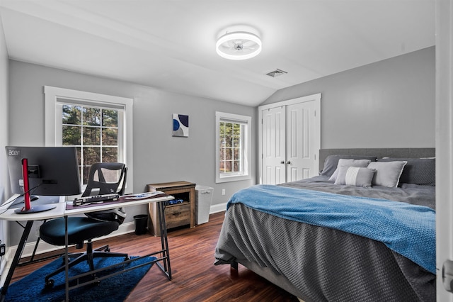 bedroom featuring baseboards, a closet, vaulted ceiling, dark wood-style floors, and visible vents