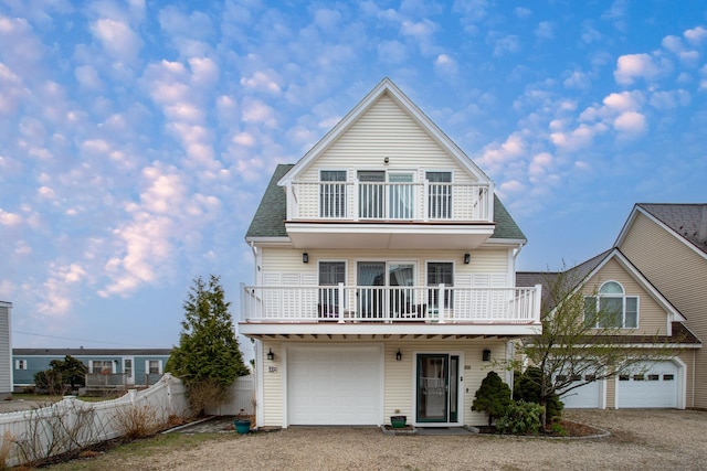 46A River St Unit A, Seabrook, NH 03874 - view of front of house with a balcony, roof with shingles, gravel driveway, an attached garage, and fence