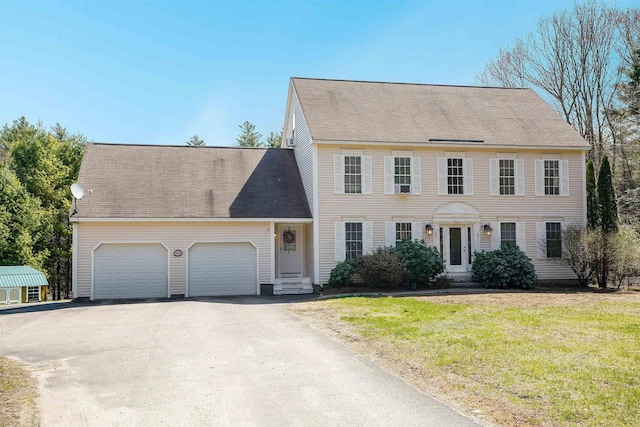 colonial house featuring a front yard, aphalt driveway, entry steps, and a garage