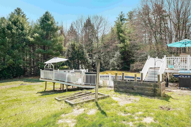 view of yard with fence, a deck, and a vegetable garden
