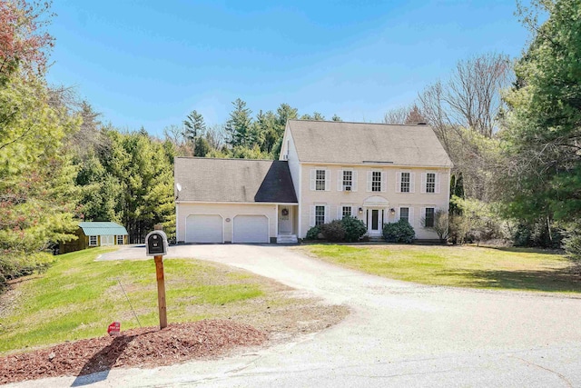 colonial house with driveway, a front yard, and an attached garage