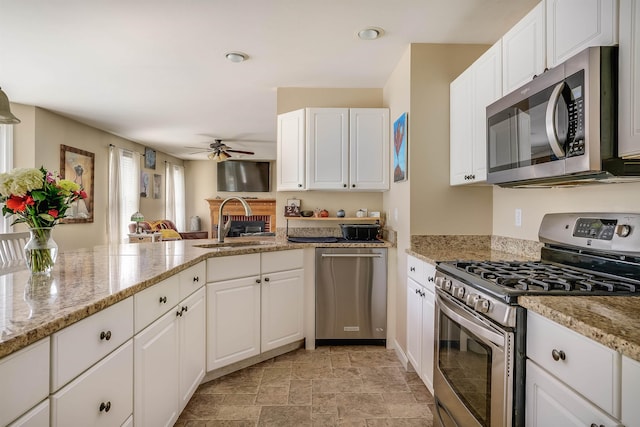 kitchen with a ceiling fan, white cabinets, appliances with stainless steel finishes, and stone finish flooring