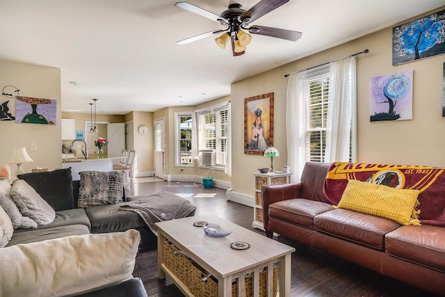 living room with dark wood-style flooring, a healthy amount of sunlight, a ceiling fan, and baseboards
