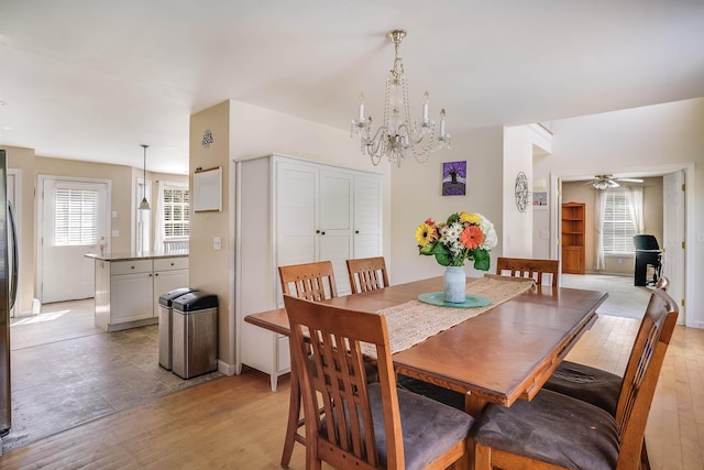 dining area featuring ceiling fan with notable chandelier, light wood-style floors, and plenty of natural light