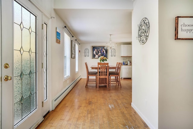 dining space with an inviting chandelier, light wood-style flooring, and a baseboard radiator