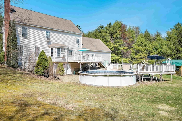 back of property with a wooden deck, a yard, a chimney, and a covered pool