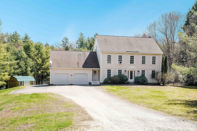 colonial home with a front lawn, an outbuilding, dirt driveway, a storage unit, and an attached garage