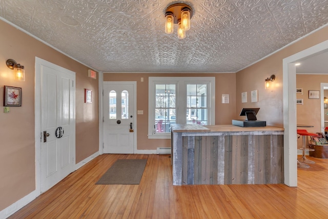 foyer featuring ornamental molding, hardwood / wood-style floors, an ornate ceiling, and baseboards