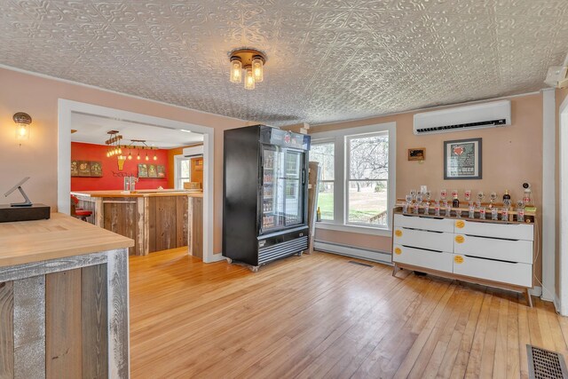 kitchen featuring hardwood / wood-style flooring, visible vents, a baseboard heating unit, an ornate ceiling, and an AC wall unit