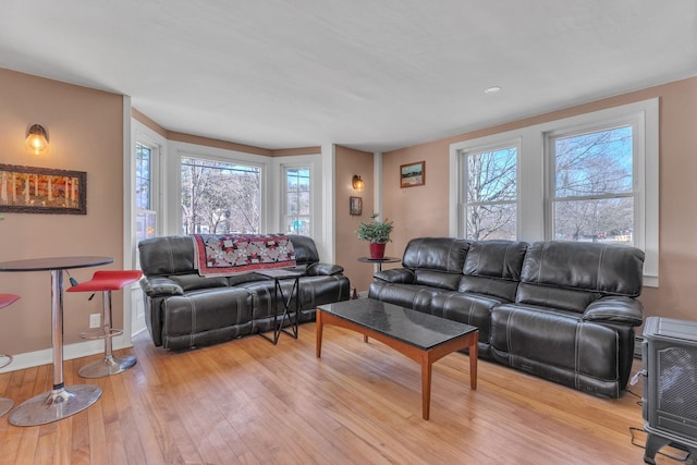 living room with baseboards, light wood-type flooring, and plenty of natural light
