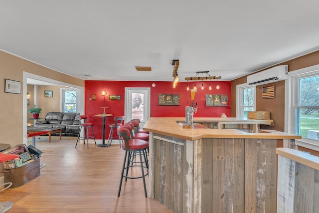 kitchen featuring a kitchen breakfast bar, light wood-style flooring, a kitchen island, and an AC wall unit