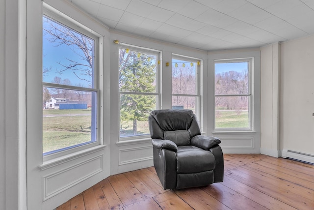 living area featuring a baseboard heating unit and light wood finished floors