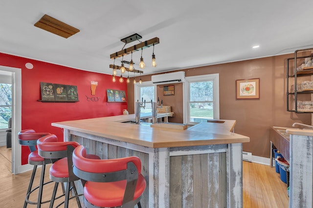 bar with a dry bar, light wood-style floors, and a wall mounted AC