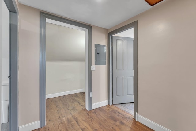 hall with electric panel, wood finished floors, and baseboards