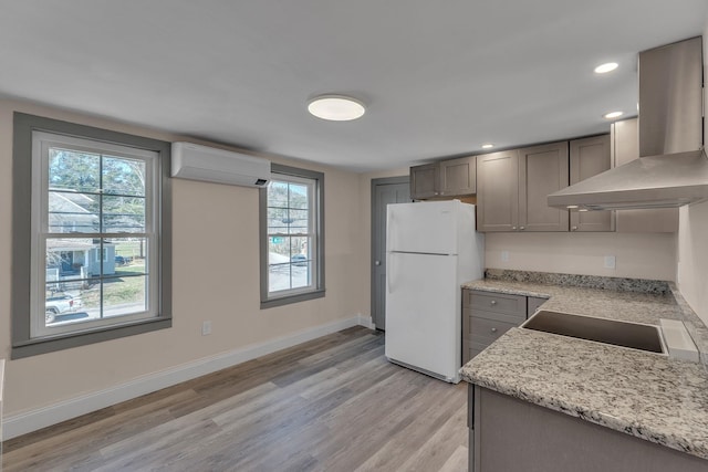 kitchen featuring a wealth of natural light, light wood-style floors, a wall unit AC, and freestanding refrigerator