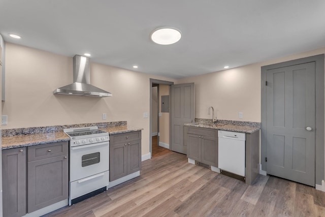 kitchen featuring wall chimney range hood, a sink, light wood-type flooring, white appliances, and gray cabinets