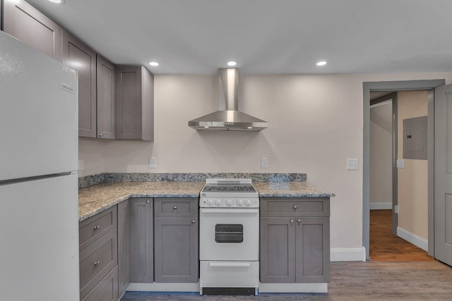 kitchen with wall chimney range hood, white appliances, electric panel, and gray cabinets