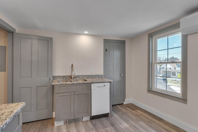 kitchen with a sink, white dishwasher, baseboards, light wood-type flooring, and gray cabinets