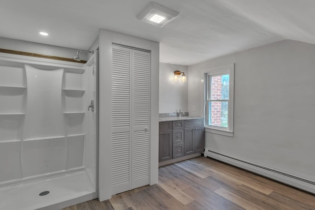 full bathroom featuring baseboard heating, a stall shower, wood finished floors, and a closet