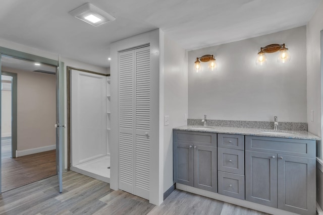 full bathroom featuring a closet, a sink, wood finished floors, and baseboards