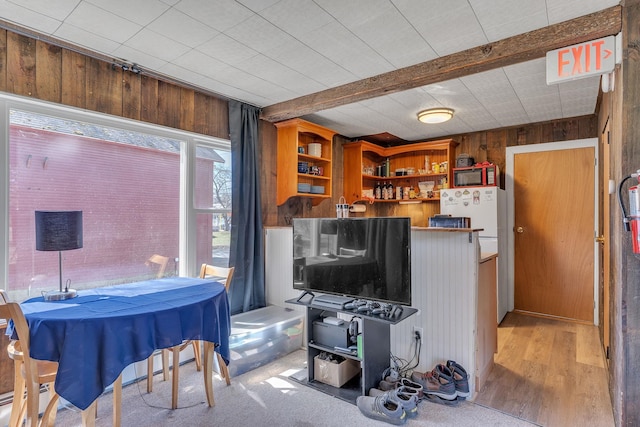 living room with wood walls, wood finished floors, and beam ceiling