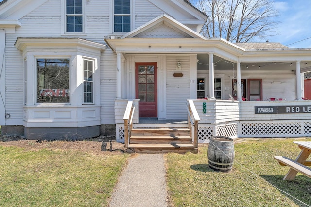 doorway to property with a lawn and a porch
