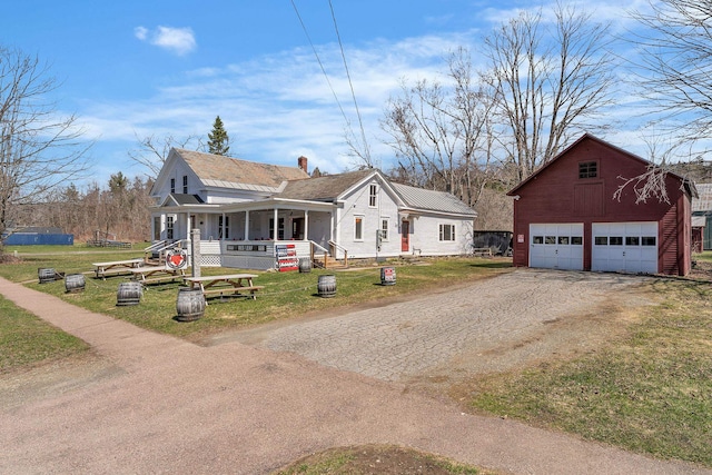 bungalow featuring a porch, a front lawn, a garage, an outdoor structure, and driveway