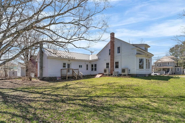 back of property featuring metal roof, a lawn, and a chimney