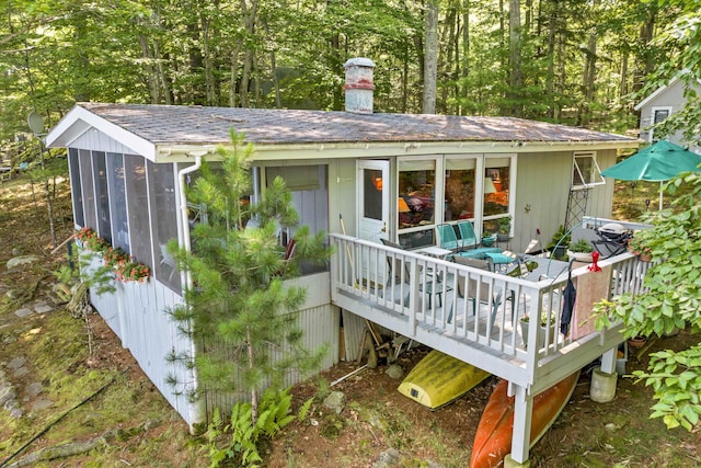 back of house with a chimney and a wooden deck