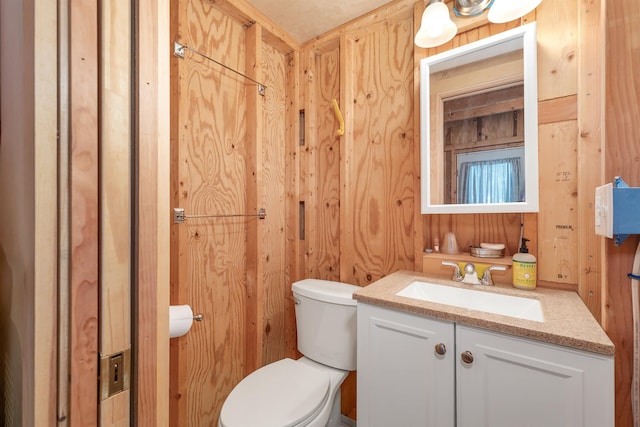bathroom featuring wooden walls, vanity, and toilet