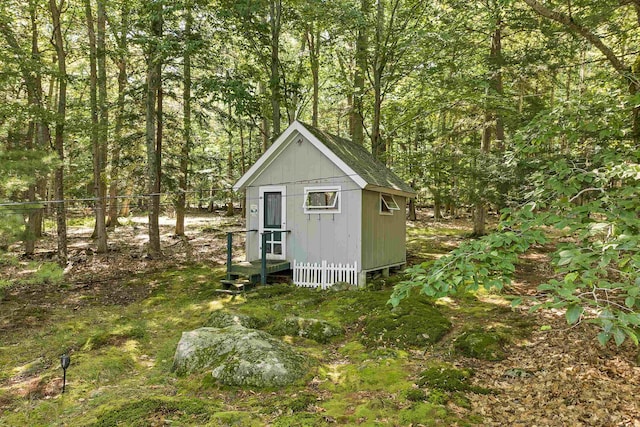 view of shed featuring a wooded view and fence