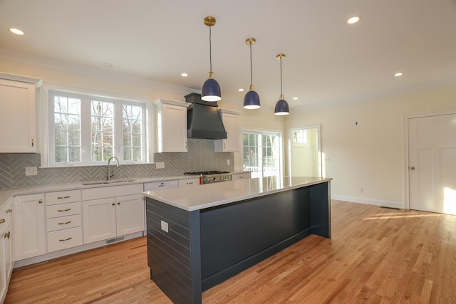 kitchen with wall chimney exhaust hood, a sink, decorative backsplash, and light countertops