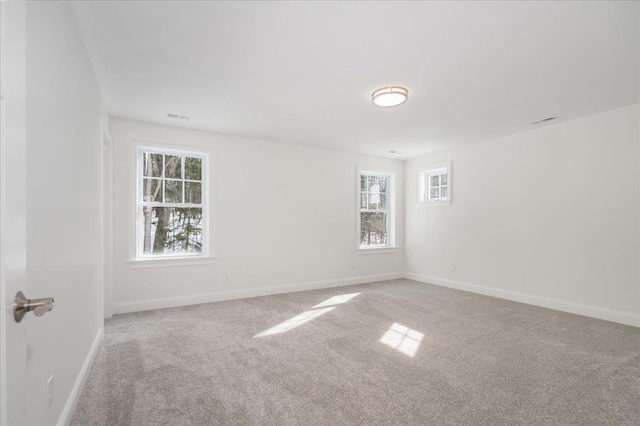 carpeted spare room featuring baseboards and a healthy amount of sunlight