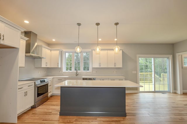 kitchen with wall chimney range hood, a healthy amount of sunlight, stainless steel appliances, and a sink