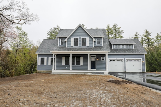 view of front of property featuring driveway, covered porch, and roof with shingles