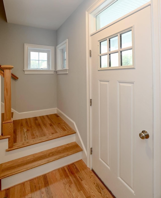 doorway with stairs, wood finished floors, and baseboards