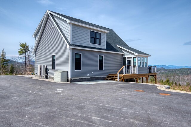back of house featuring a shingled roof and a deck with mountain view