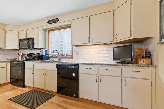 kitchen featuring black appliances, a sink, tasteful backsplash, and light wood-type flooring