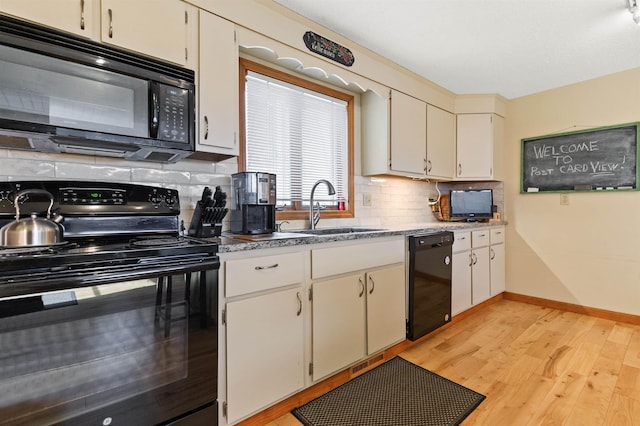 kitchen featuring tasteful backsplash, black appliances, a sink, baseboards, and light wood-type flooring
