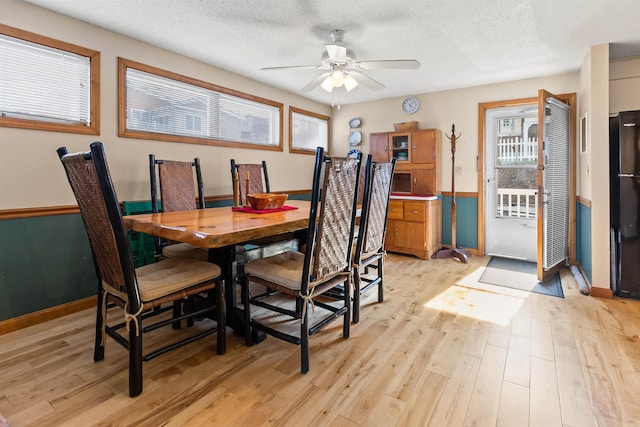 dining space with a textured ceiling, light wood-style floors, a ceiling fan, and baseboards