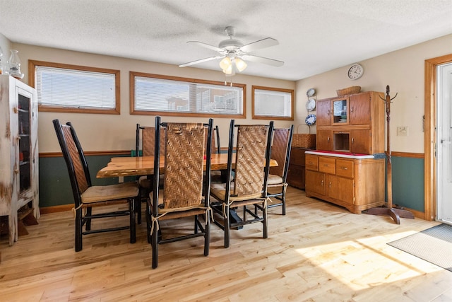 dining area featuring a ceiling fan, a textured ceiling, and light wood-style flooring