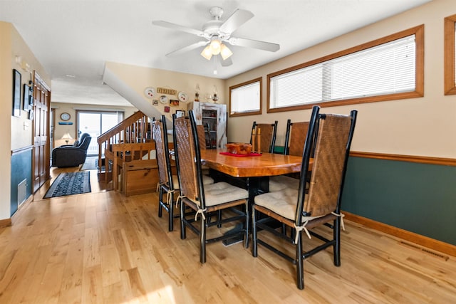 dining room featuring light wood-style floors, a ceiling fan, and baseboards