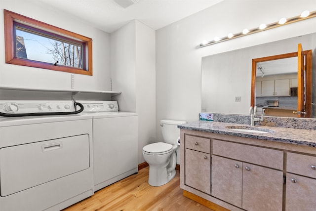 bathroom with wood finished floors, toilet, washing machine and clothes dryer, and vanity